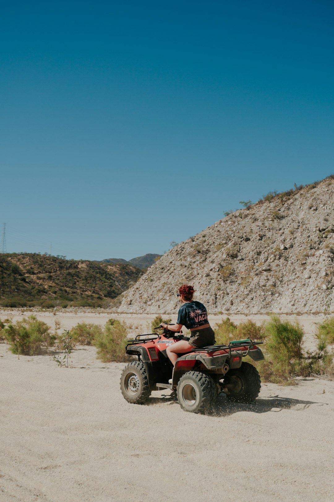 man riding red atv on brown dirt road during daytime