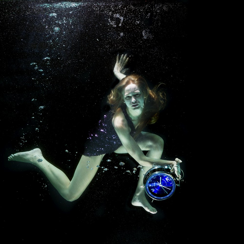 woman in blue and white bikini top and blue and white goggles under water