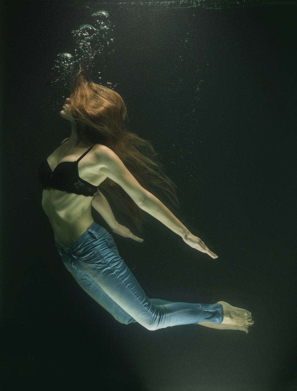 Mujer con sujetador negro y vaqueros azules bajo el agua
