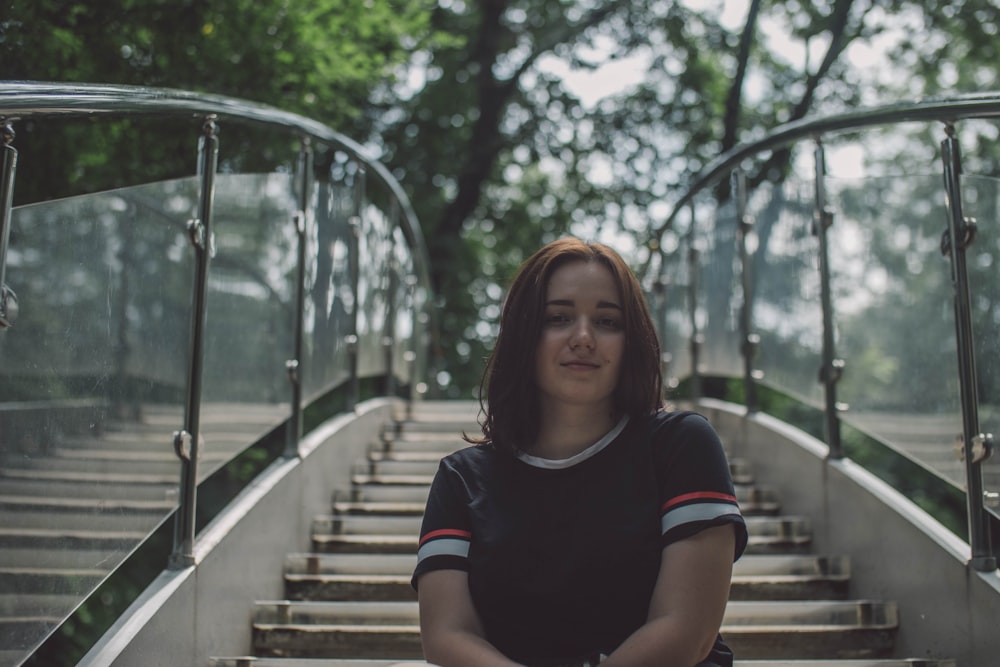 woman in black and white crew neck t-shirt standing on brown wooden bridge during daytime