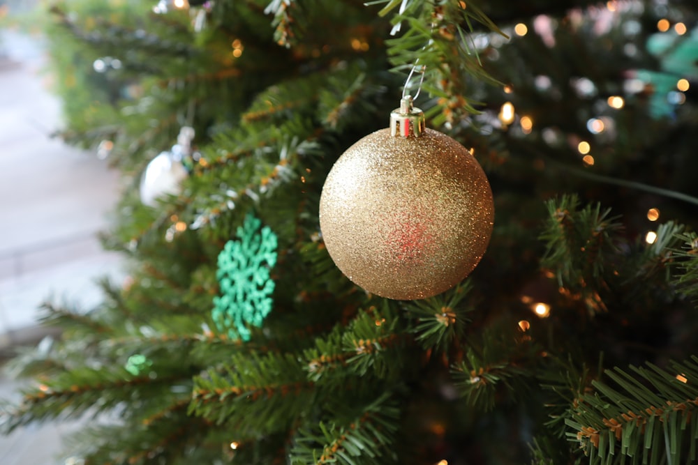 gold bauble hanging on green christmas tree
