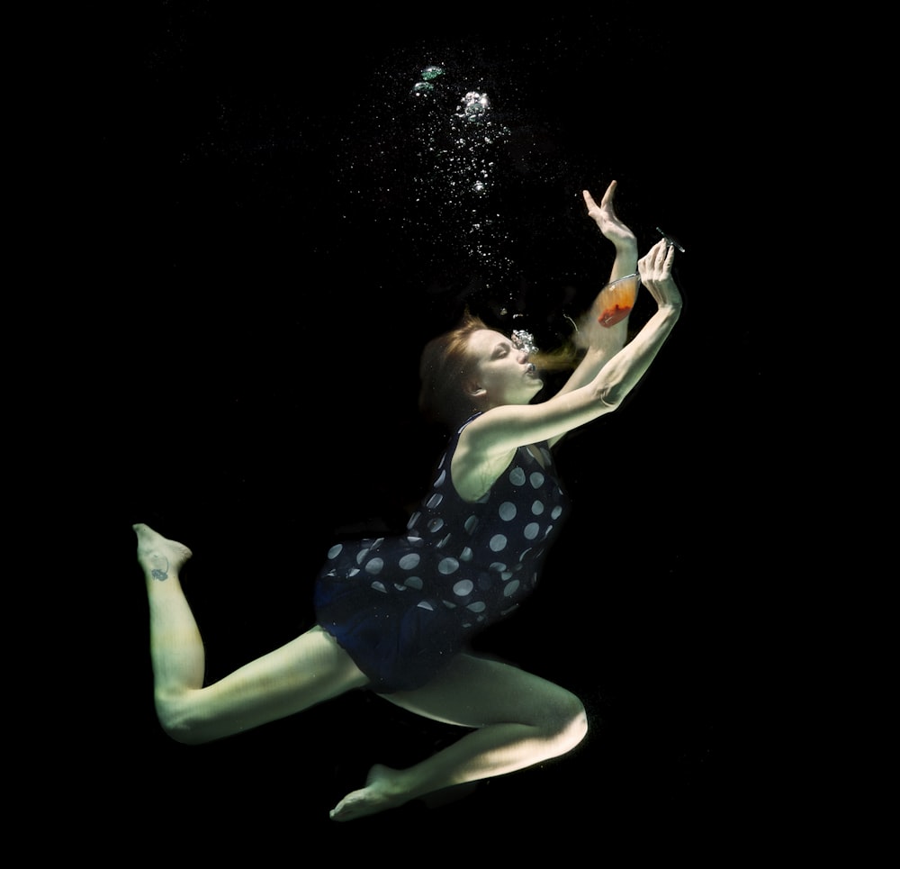 woman in blue and white polka dot dress lying on white surface