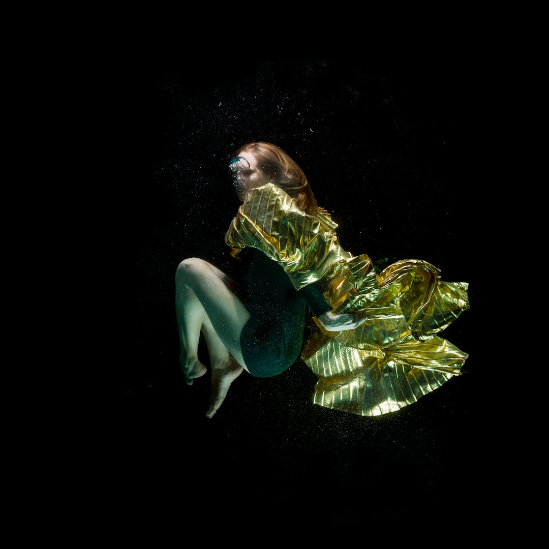 woman in green dress lying on black surface