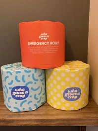 Colorful packs of toilet paper rolls arranged on store shelves.