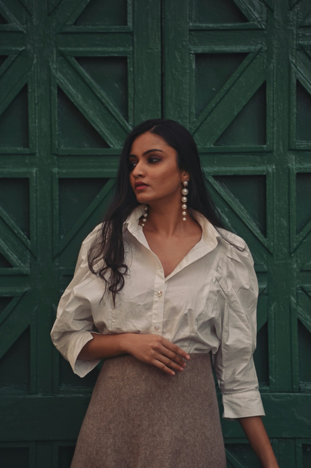 woman in white button up shirt standing beside green wooden door