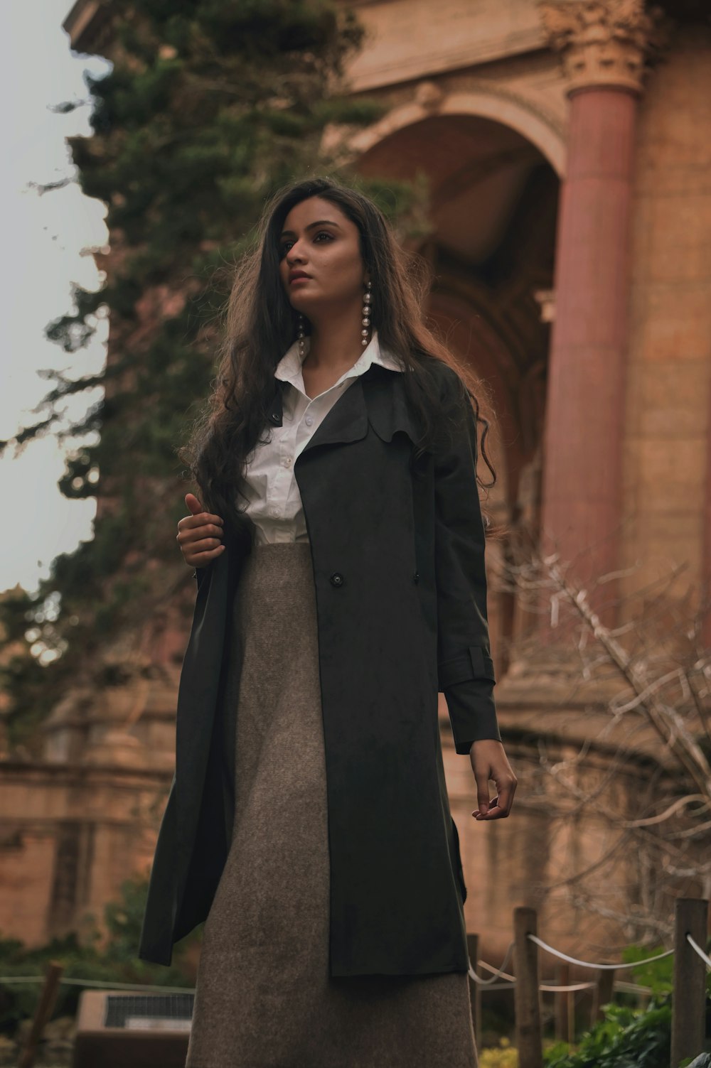 woman in black coat standing on brown wooden pathway during daytime