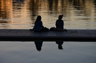 Two people sitting by the water, considering mortgage and financing for a waterfront property.