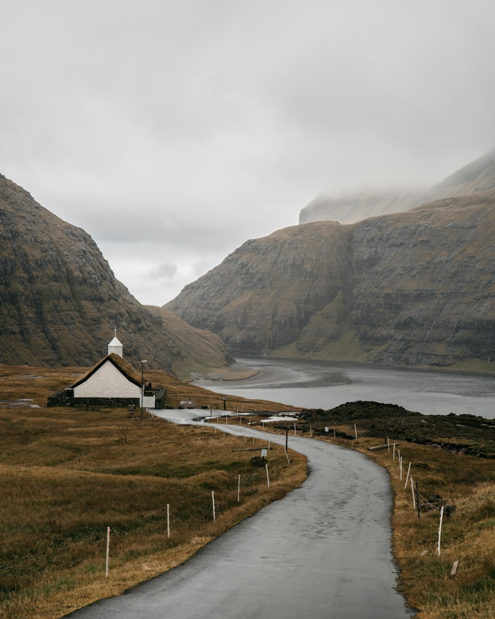 white and brown house near body of water and mountain during daytime