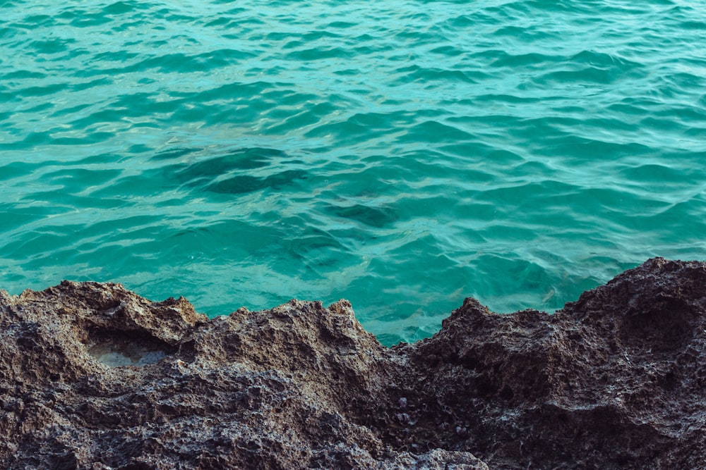 brown rock formation beside body of water during daytime