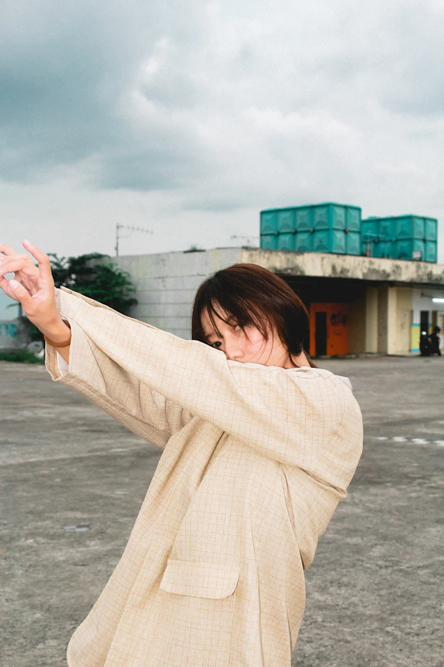 A woman in a beige coat on a concrete floor