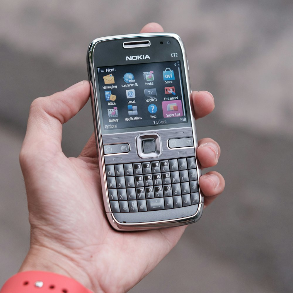 Persona sosteniendo un teléfono Nokia QWERTY gris