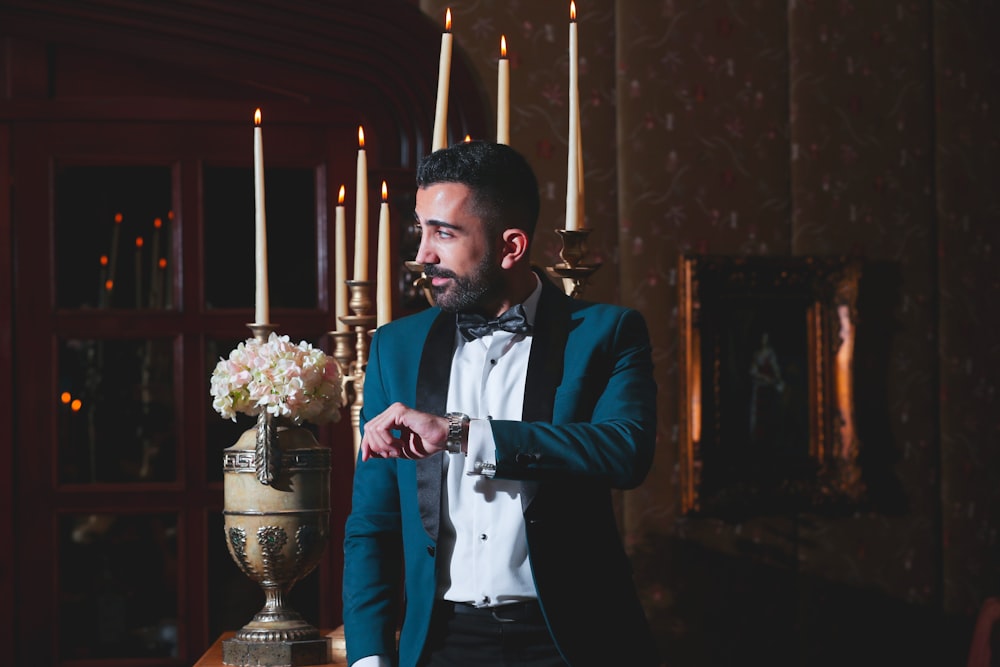 man in black suit jacket holding candle stick