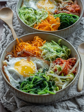 A vibrant plate of bibimbap with fresh vegetables and a perfectly cooked egg on top.