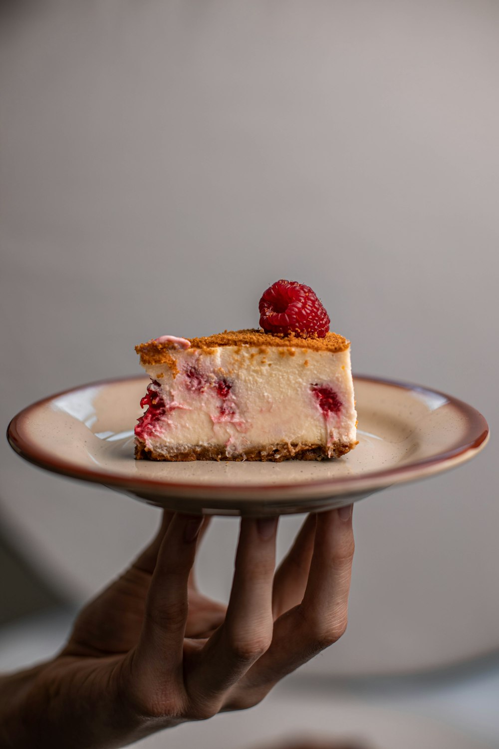 personne tenant un gâteau aux fraises sur une assiette en céramique blanche