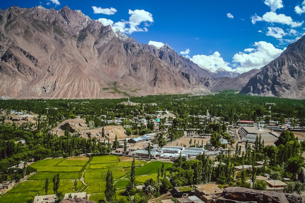 green grass field near mountain under blue sky during daytime