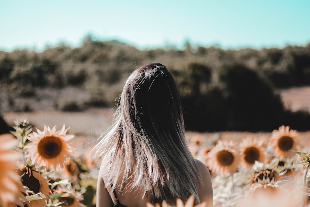 woman in white tank top standing on brown field during daytime