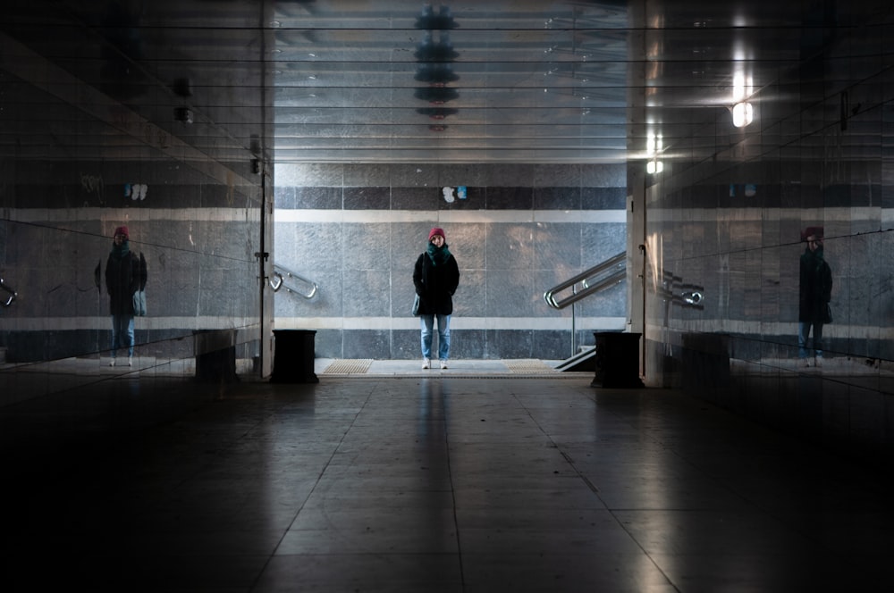 man in black jacket walking on white tiled floor