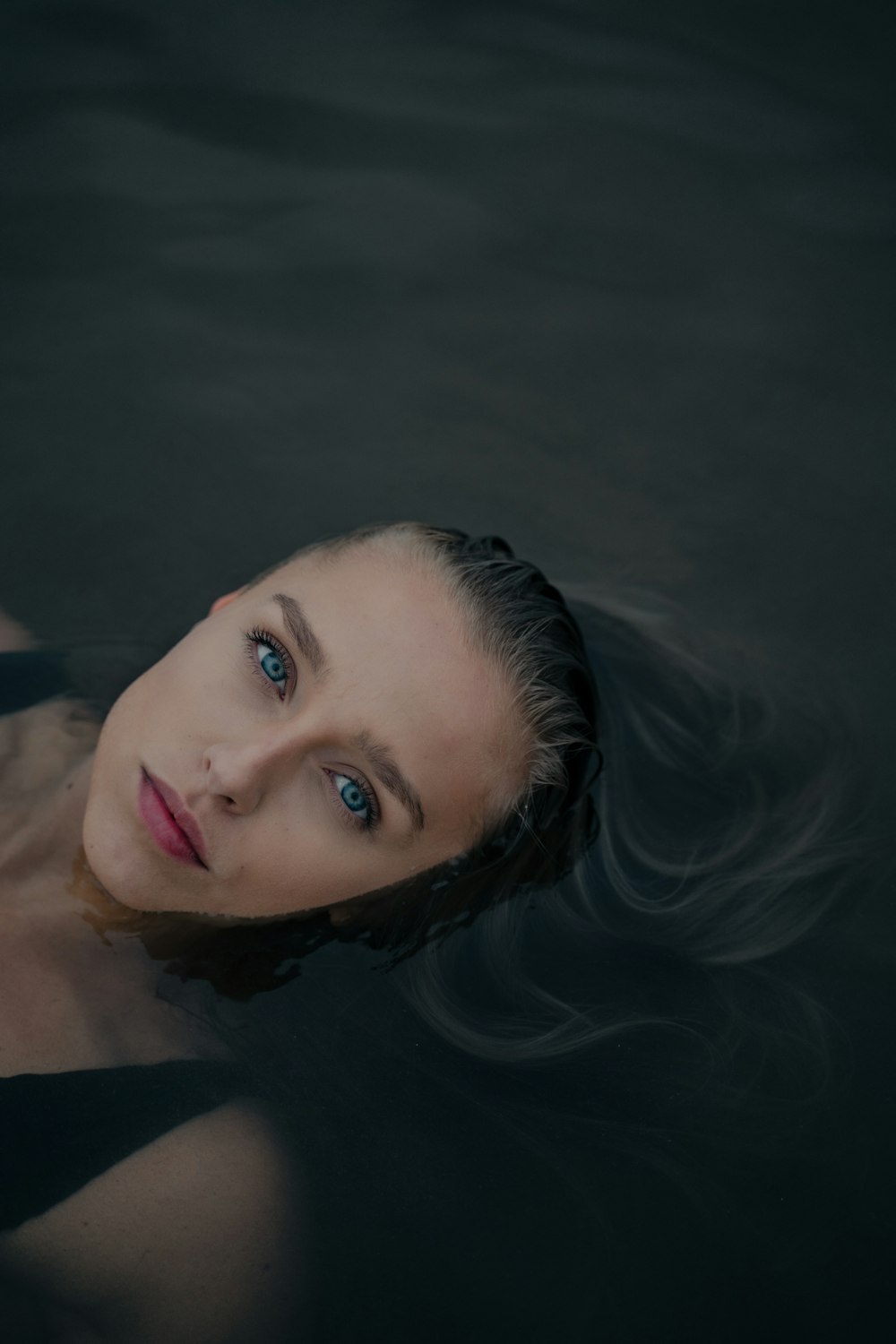 woman in black hair lying on water