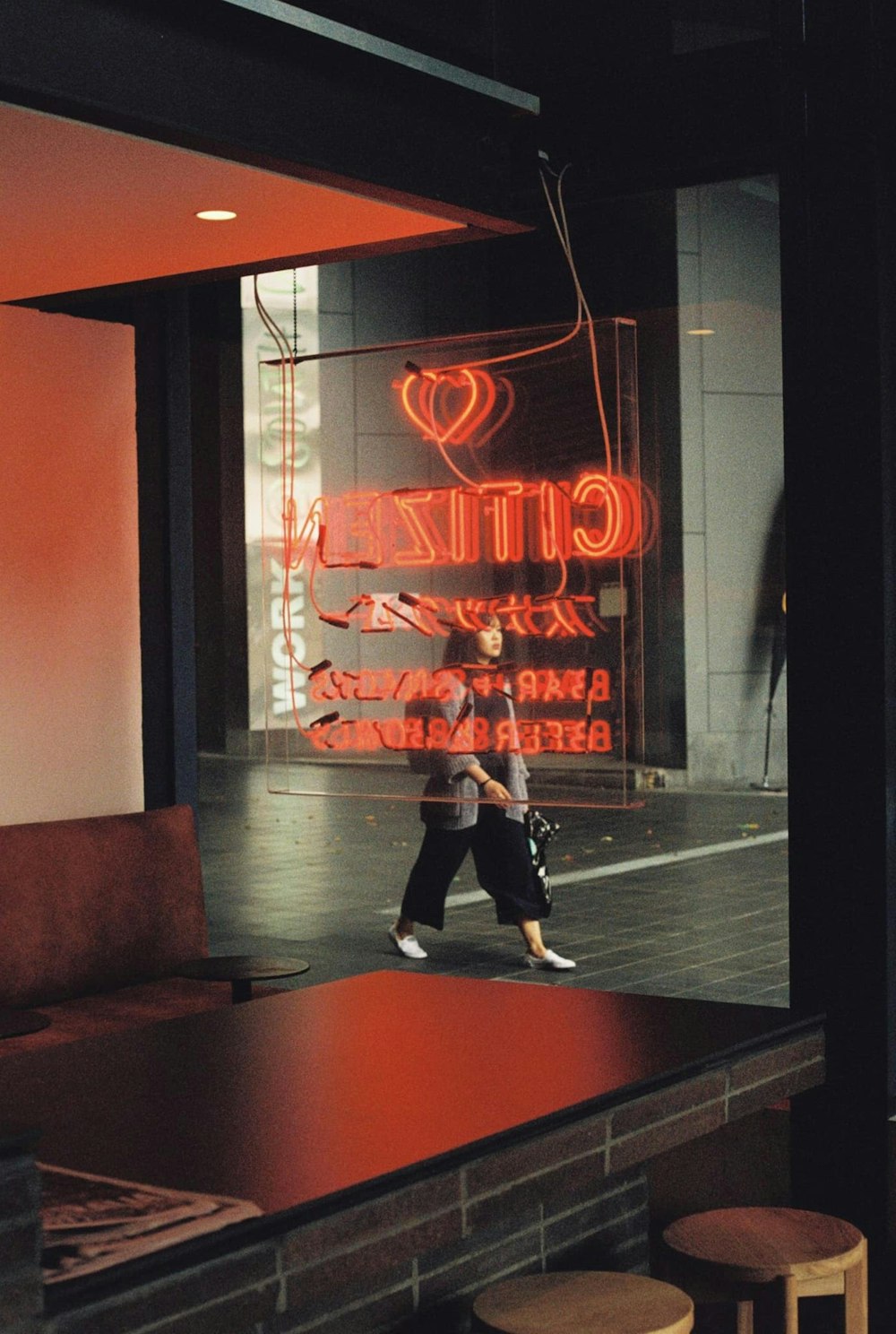 man in black jacket and black pants standing near red and white neon sign