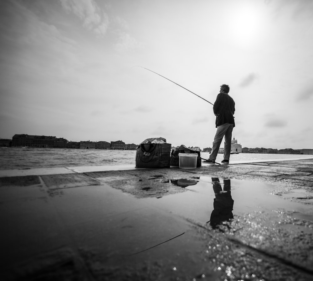 man in black jacket and pants fishing on beach during daytime