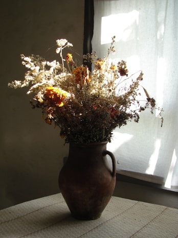 yellow and white flowers in brown ceramic vase