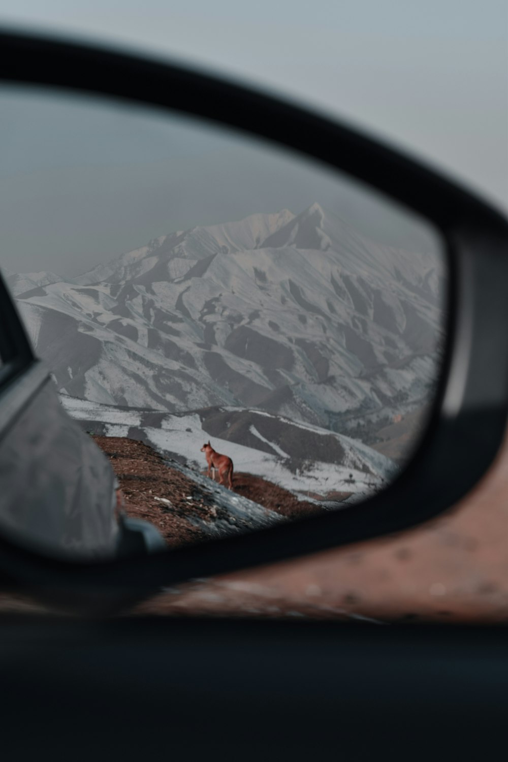 black car side mirror reflecting snow covered mountain during daytime