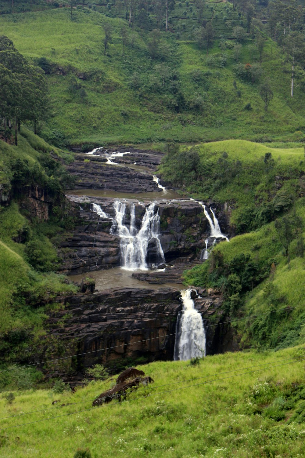 waterfalls in the middle of green grass field