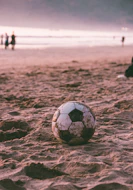 black and white soccer ball on brown sand