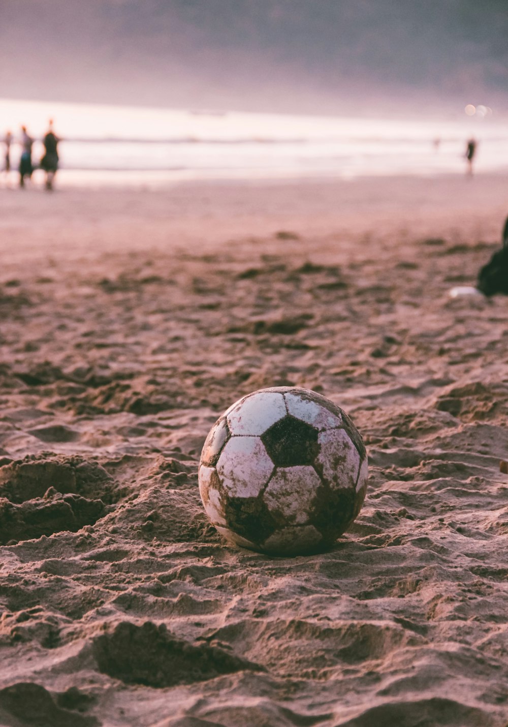 black and white soccer ball on brown sand