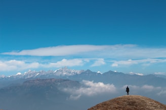 person standing on rock formation near snow covered mountains during daytime