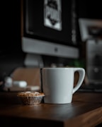 white ceramic mug beside brown round biscuit