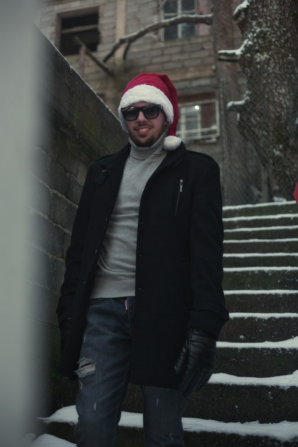 man in black jacket and red knit cap standing on stairs