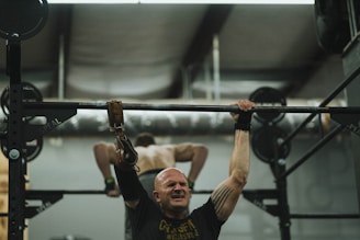 man in black crew neck t-shirt holding black barbell
