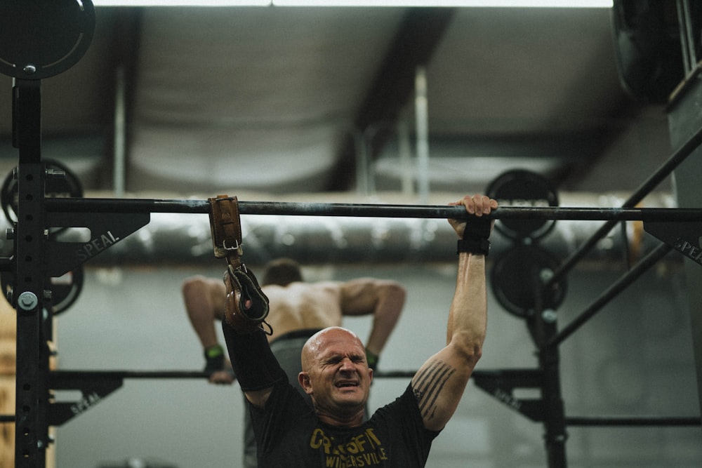 man in black crew neck t-shirt holding black barbell