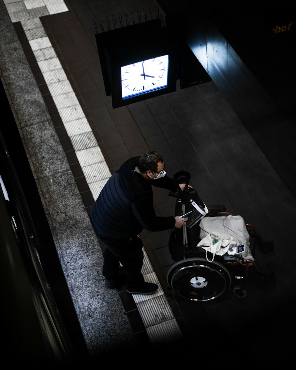 man in black jacket and blue denim jeans sitting on black wheel chair