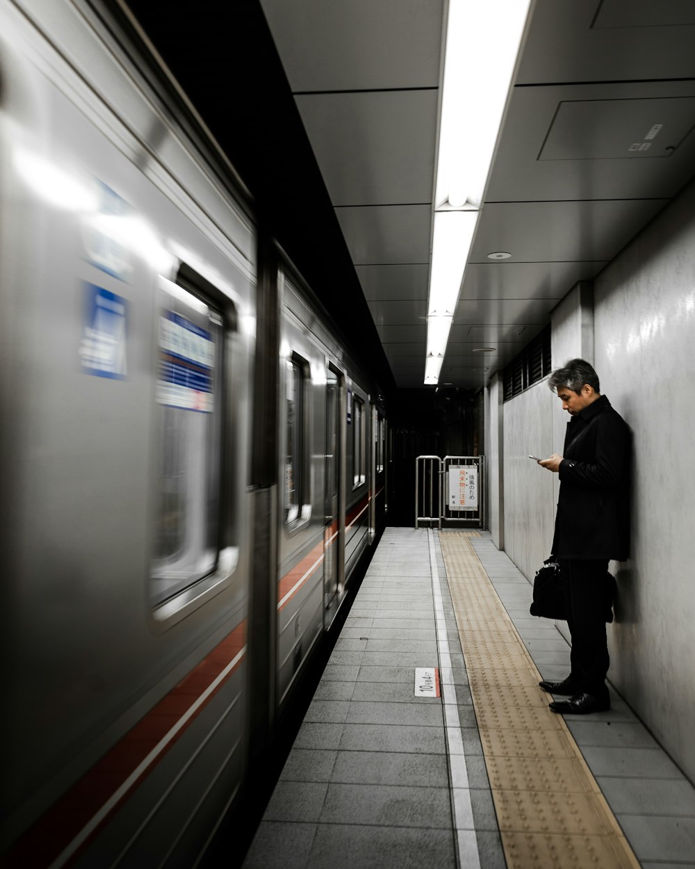 man in black coat standing beside train