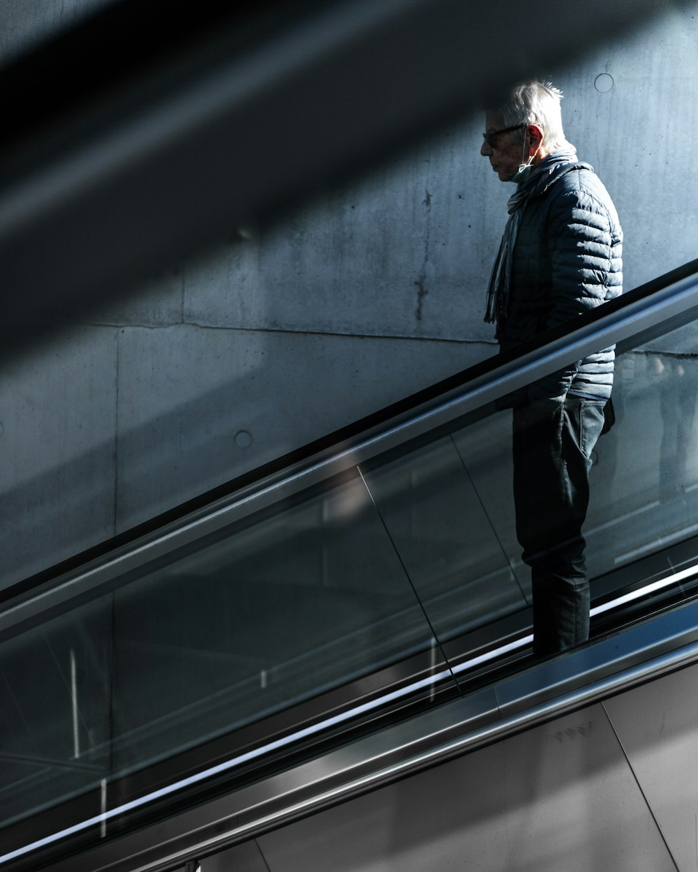 man in black jacket and black pants standing on escalator
