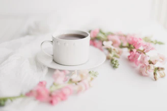 A cozy corner featuring a petalclay ceramic cup beside a blooming bouquet.