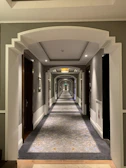 Spacious hotel corridor showcasing intricate wall paneling and ambient lighting.