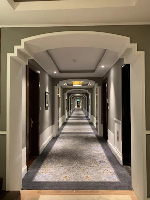 Spacious hotel corridor showcasing intricate wall paneling and ambient lighting.