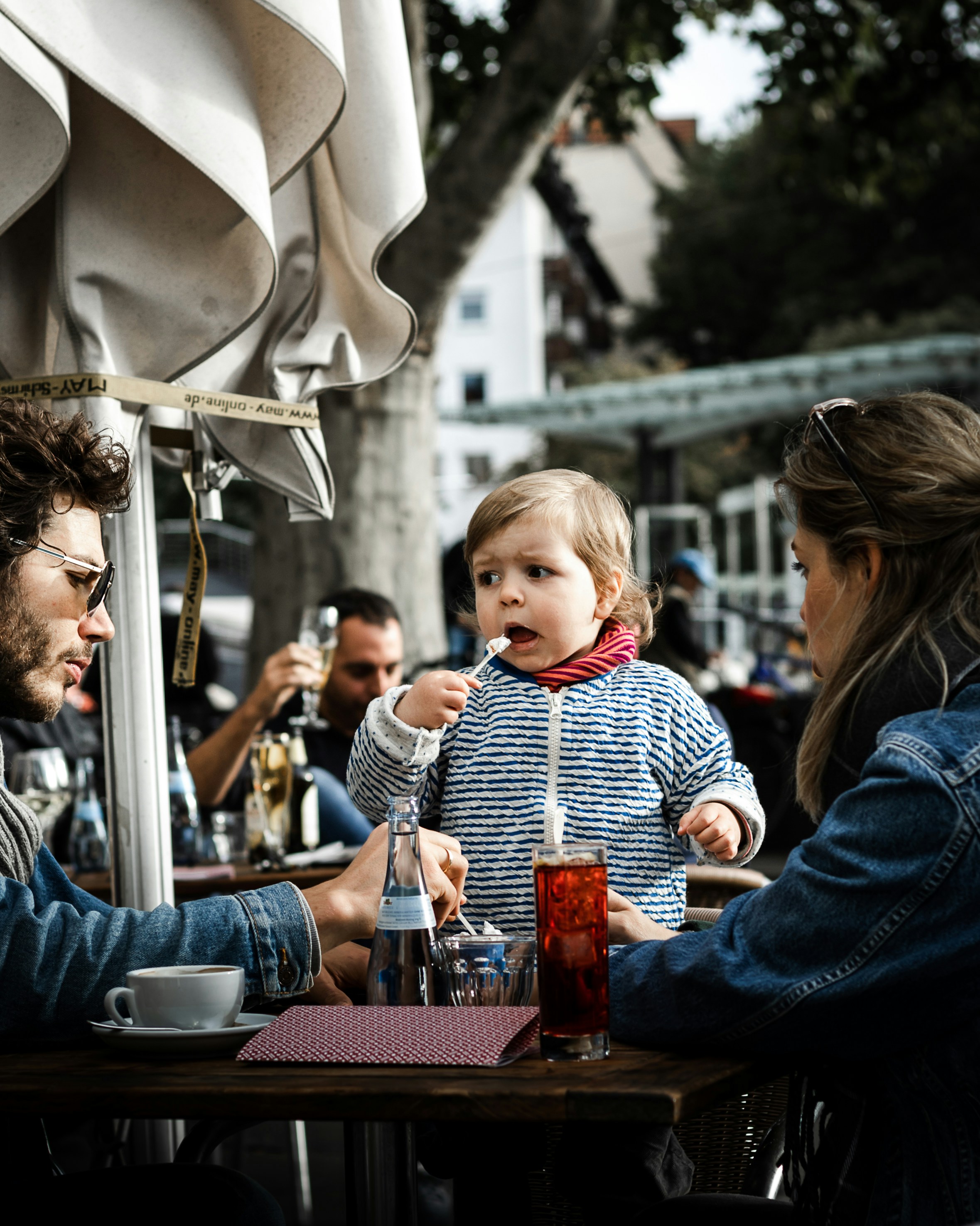 woman in blue denim jacket carrying baby in white and black striped long sleeve shirt