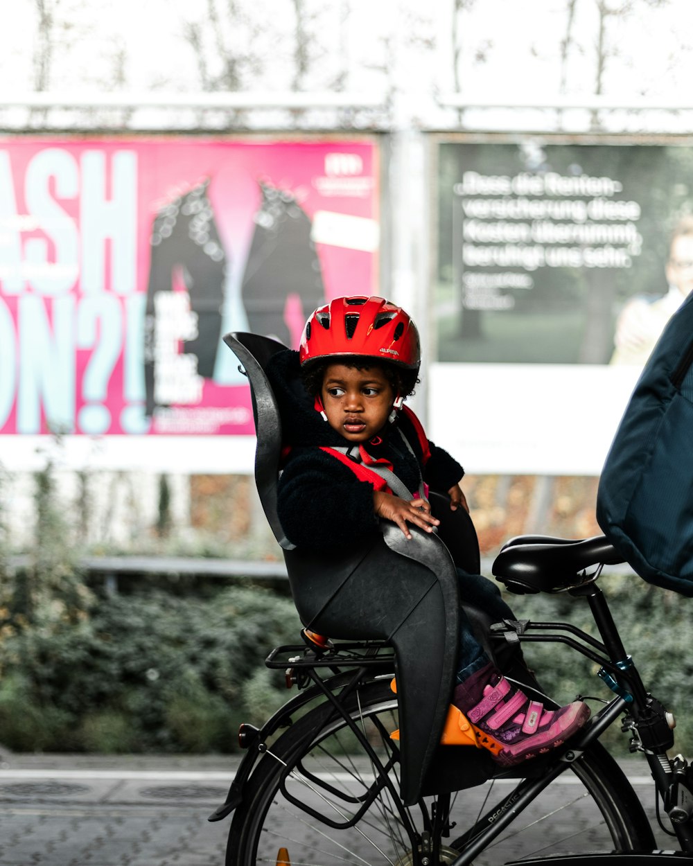 woman in black jacket and red helmet riding on bicycle