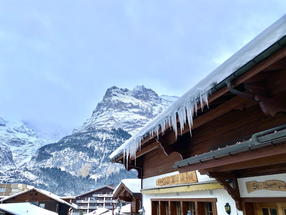 brown wooden house near snow covered mountain during daytime