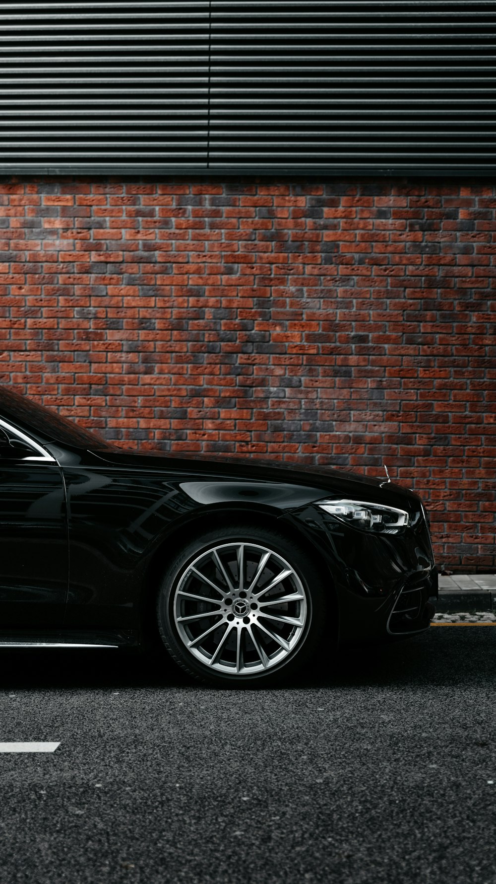 black car parked beside brown brick wall