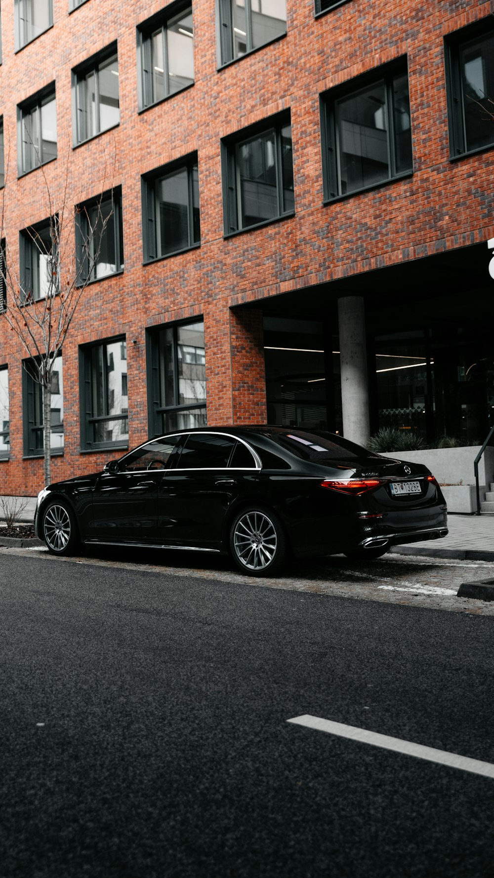 black sedan parked beside brown concrete building during daytime