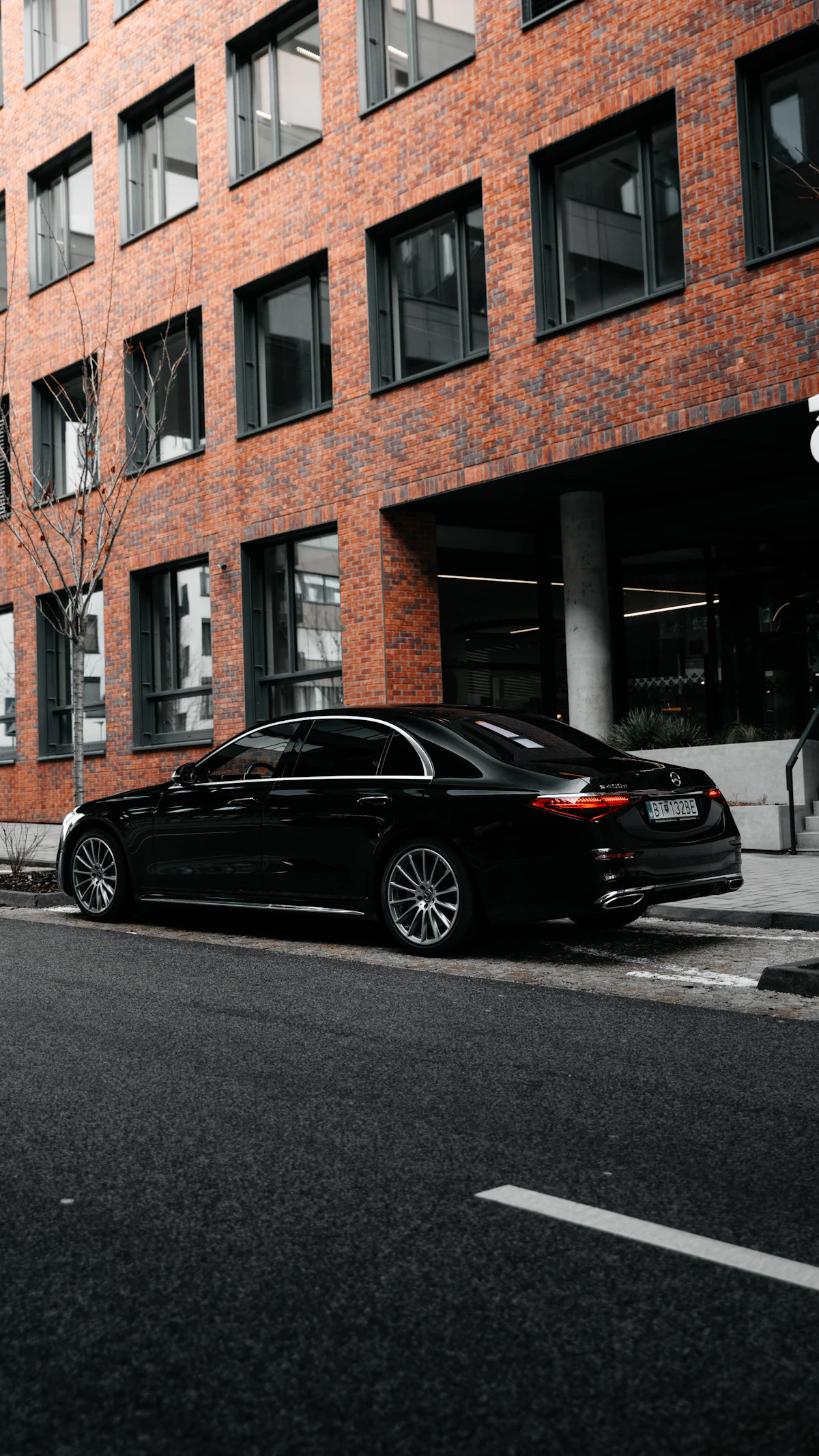 Black sedan beside a brick building