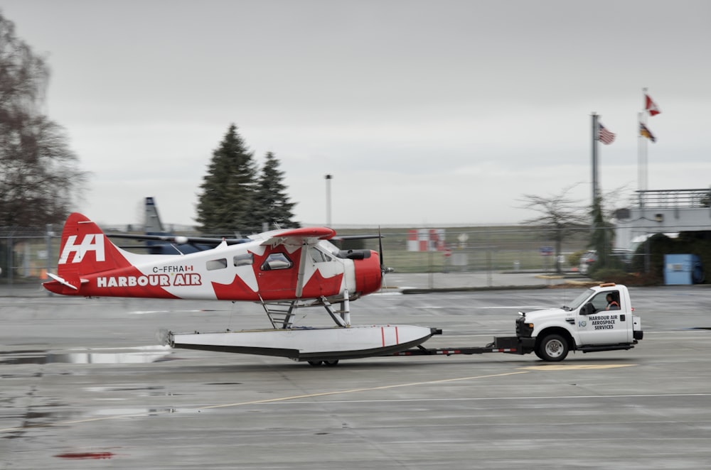 a red and white plane being towed by a tow truck