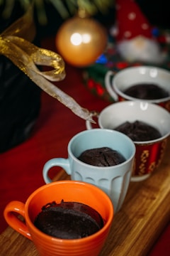 A set of three custom mugs arranged on a rustic wooden table with holiday decorations