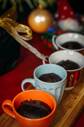 A set of birthday-themed mugs arranged on a pastel pink background with confetti.