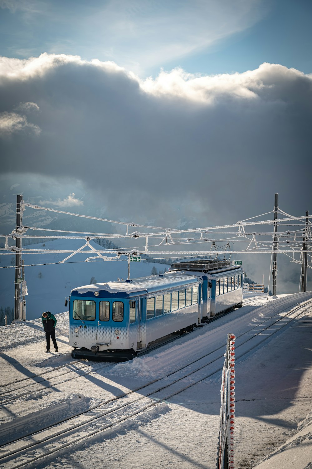 blue and white train on rail under cloudy sky during daytime